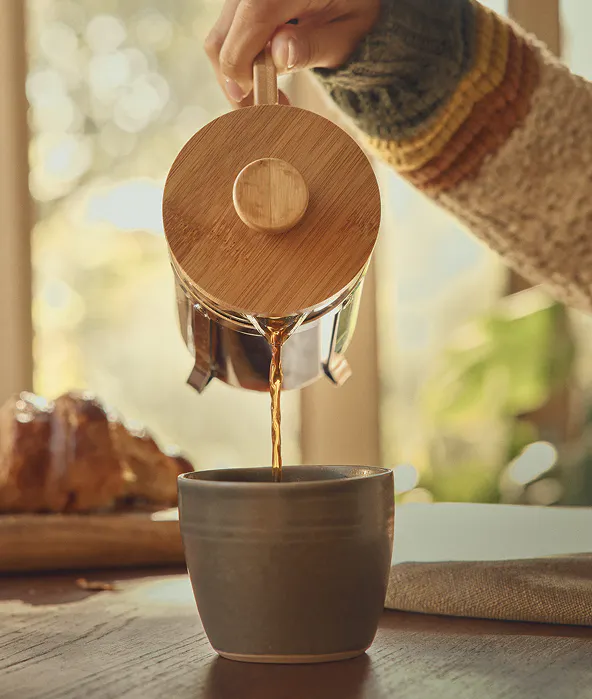 Coffee being poured into a mug from a french press
