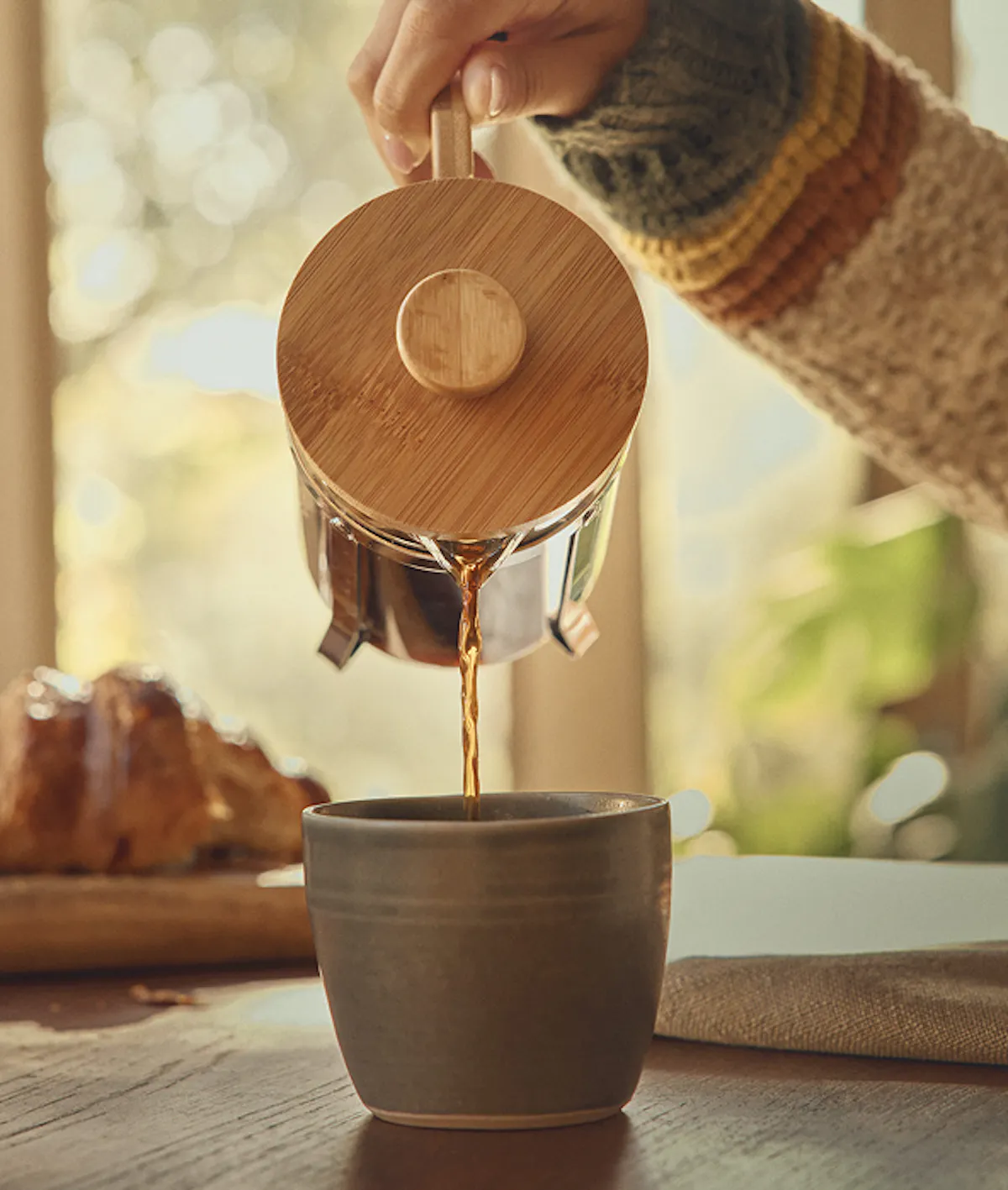 Coffee being poured into a mug from a french press