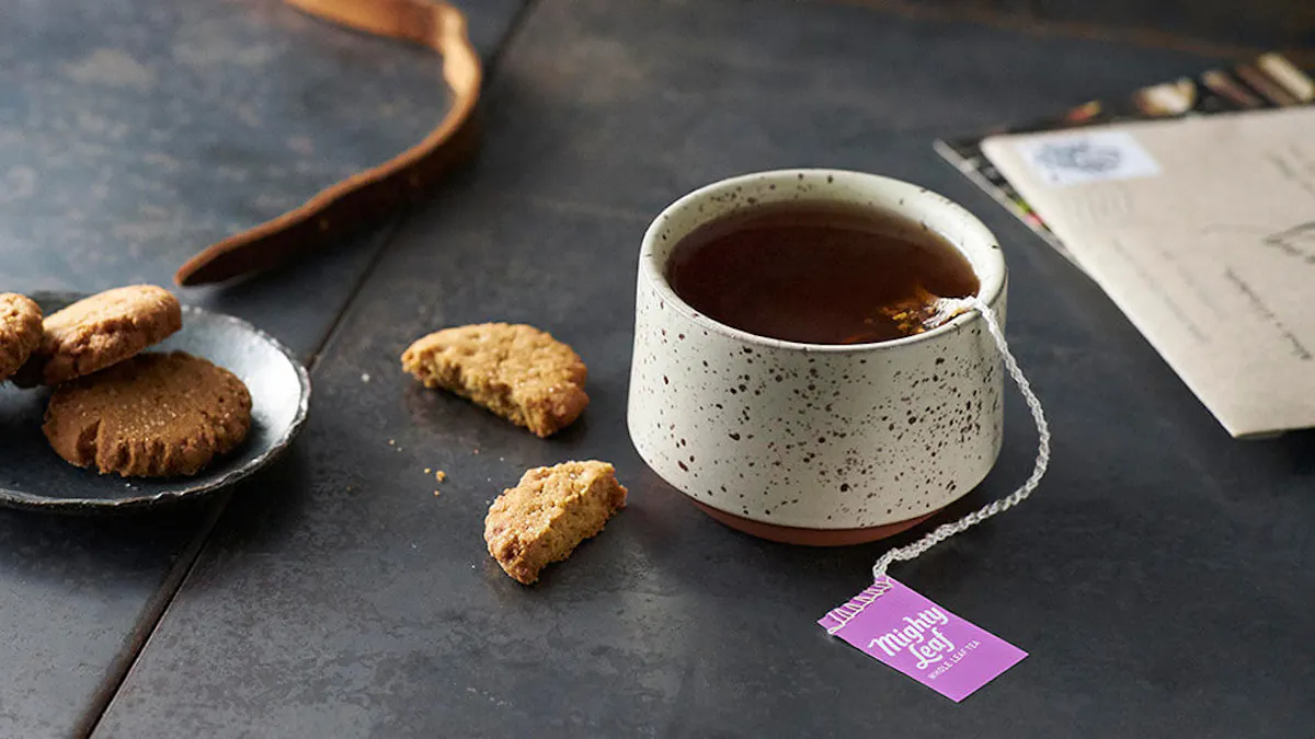 Ceramic mug with tea and cookies on a dark surface