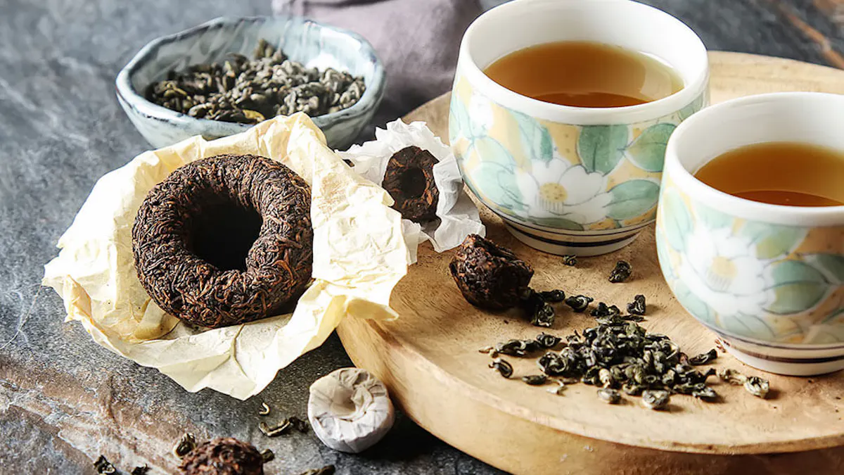 Two cups of tea on a wooden board with tea leaves and a tea bag.